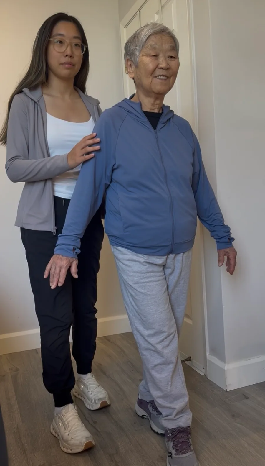 Physiotherapist supporting an older adult during a walking exercise.