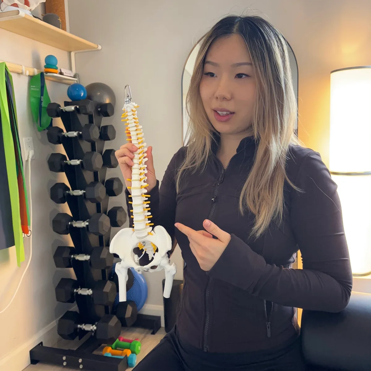 Physiotherapist explaining spinal anatomy using a model.